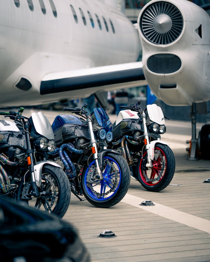 Three custom motorcycles parked by a jet plane, showcasing a fusion of aviation and bike culture.