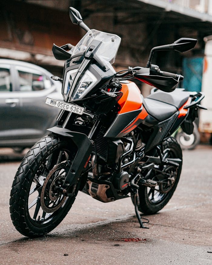 A sleek orange and black sports bike parked on an urban street, showcasing modern design and power.